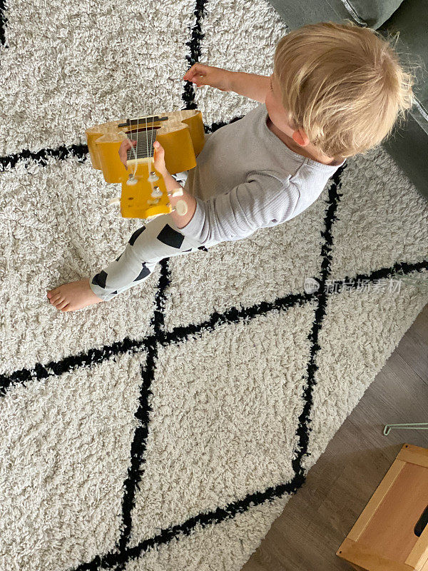 Toddler boy playing his toy guitar